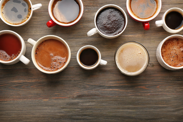 A directly overhead view of three cups of coffee on a light-colored background